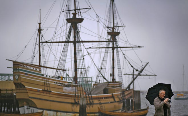 Steve Abery of Essex, England, takes a picture along the Plymouth waterfront in the rain. Abery is visiting New England with a group tour. Behind him is the Mayflower II, which, like its namesake, sailed from England to Plymouth.