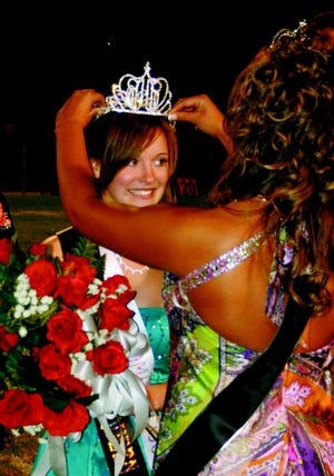 Beth Reynolds manages her first smile as the 2010 Homecoming Queen as Michelle Castagne, the 2009 Queen, places the crown on Reynolds.