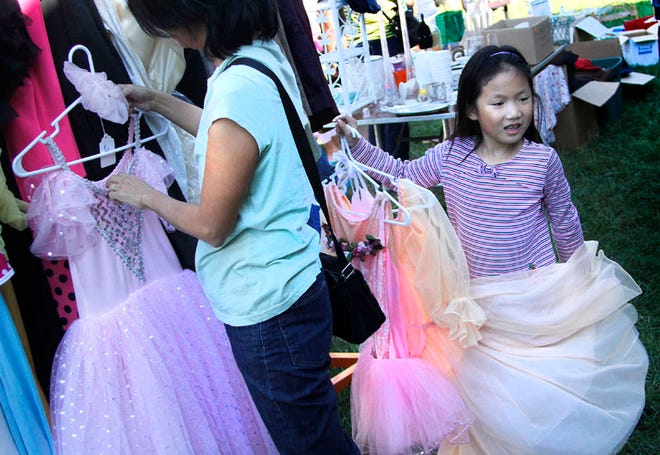 Ellie Uchida-Prebor, 7, holds some dresses she picked out while her mother Yoko Uchida looks through more costumes and dresses at the Great Halloween Costume and Garage Sale at Pofahl Studios in Gainesville on Saturday.