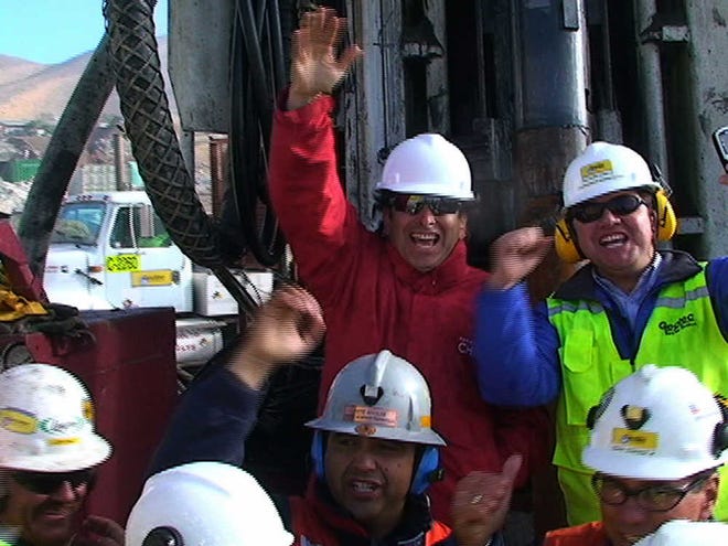In this still image taken from a video, Chile Minister of Mining Laurence Golborne, top center, celebrates Saturday with workers and other officials as the T-130 drill reaches 2,041 feet below the surface point after 33 days of drilling to reach trapped miners.