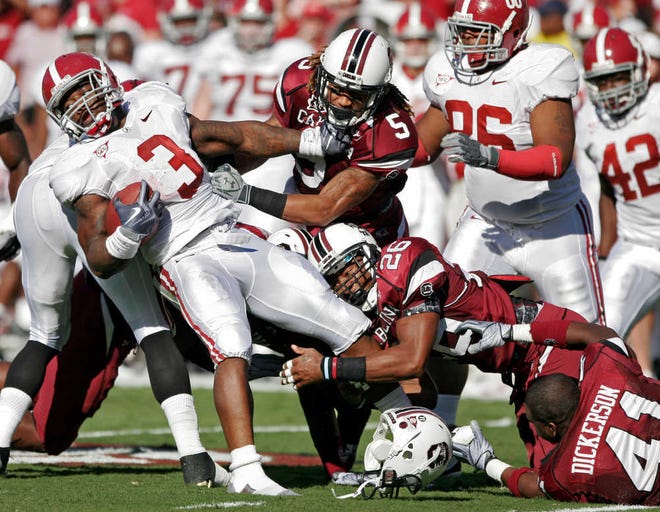Alabama running back Trent Richardson, left, is brought down by South Carolina safety Antonio Allen (26) and cornerback Stephon Gilmore (5) during the first half of an NCAA college football game, Tuesday, Nov. 9, 2010, at Williams-Brice Stadium, in Columbia, S.C. (AP Photo/Brett Flashnick)