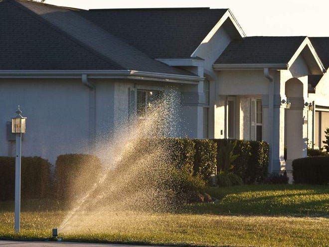 A resident of Quail Meadow subdivision waters her lawn Friday morning.