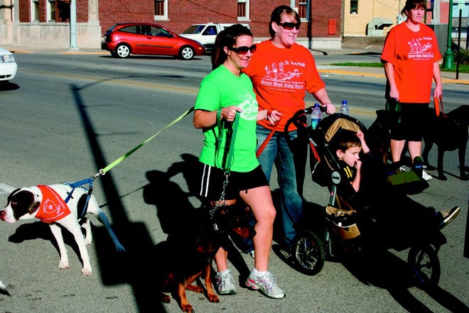 Particiapnts in the Western Illinois Animal Rescure Doggie Jog, both human and canine, walk down Broadway Saturday in Monmouth. Between 20-25 participants helped the group raise over $400. Mike Snell won the race with George Ewalt second and Arlene Smith third. About 15 dogs also completed the race.