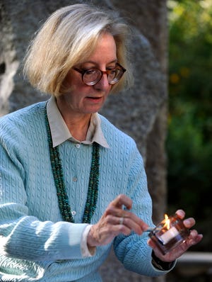 Chaplain Natalie Austrian lights a candle in the Etham Efthim Healing Garden at the Mariam Boyd Parlin residence of Wayside Hospice Friday.