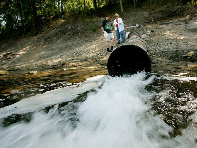 In this file photo, Mark and Annette Long do sample tests of the waters spewing out of a pipe that connects to a local chicken plant. The pipe is located near the Suwannee River State Park.