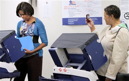 Amanda Deisch, right, takes a photo as first lady Michelle Obama casts her ballot, Thursday, Oct. 14, 2010, at an early voting location in Chicago. (AP Photo/M. Spencer Green)