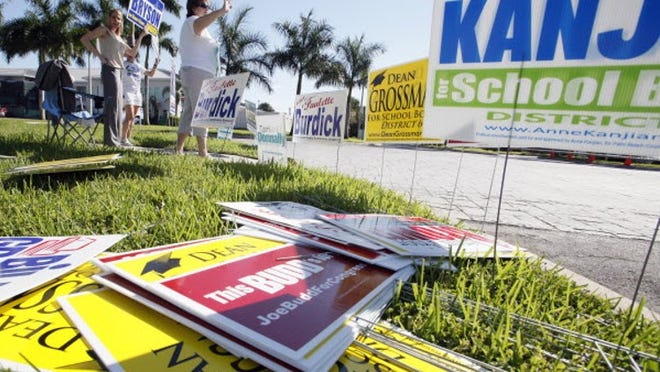 WEST PALM BEACH - Candidates and their supporters wave signs outside the Supervisor of Elections office Monday morning, the first day of early voting.