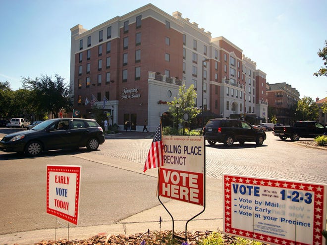 Signs remind people that early voting got under way Monday and continues through Oct. 30.