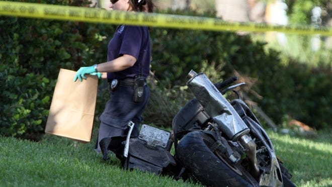 An accident scene investigator gathers evidence from a motorcycle fatality on Okeechobee Blvd., and Benoist Farms, west of West Palm Beach.
