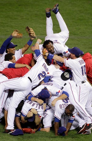 The Texas Rangers' Vladimir Guerrero leaps on his teammates after the Rangers advanced to the World Series with a 6-1 win over the New York Yankees in Game 6 of the American League Championship Series on Friday.