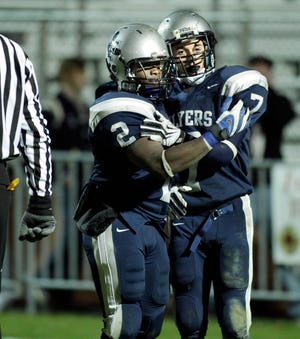 Framingham's Travis Hayes (right) gets congratulations from David Odhiambo for catching a pass and running in for a touch down to make it 13-12 Framingham in Friday night's football game with Milton.
