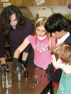 East Park Elementary School teacher Lisa Burgess, left, shows her students, left to right, Madison Thompson, Justin Maniquis and Jordan Miller a mirror making project using nano technology at the school in Danville Ill. Science has always been the study of really big things, but a group of eight Danville-area teachers is challenging students to think small instead by are introducing nanotechnology into their classrooms, using hands-on experiments to teach students about the application of some of the smallest known particles on the planet.