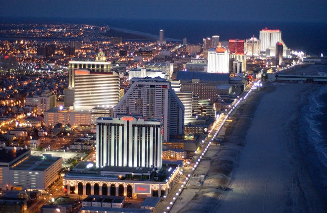 The coast along Atlantic City glows with lights from the casinos and boardwalk at night.