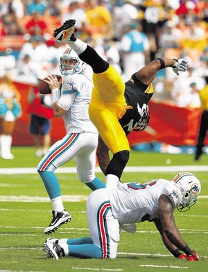 Steelers LB James Harrison dives over Dolphins’ Lousaka Polite while trying to tackle QB Chad Henne, left, on Sunday.