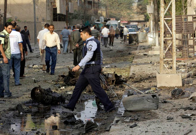 An Iraqi policeman stands guard at the scene of a car bomb attack in front of a Syrian Catholic Church, in Baghdad, Iraq, Monday Nov. 1, 2010. Islamic militants held around 120 Iraqi Christians hostage for nearly four hours in a church Sunday before security forces stormed the building and freed them, ending a standoff that left dozens of people dead, U.S. and Iraqi officials said.