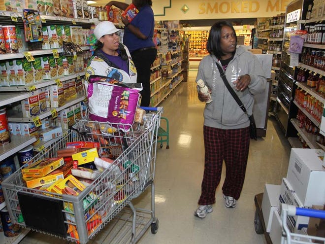 Dionne Spikes, left, and her sister, Melinda Patterson, buy food at a Cincinnati Kroger food store. Americans relying on government benefits are doing their homework to stretch the payments.