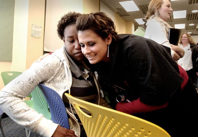 Erin Carrillo, right, a resident assistant at Sol House, a transitional living program for homeless youths, hugs former Sol House resident Krystal Whitaker Thursday night. The two attended a gathering at the Columbia Public Library at which homeless and formerly homeless youths told their stories.