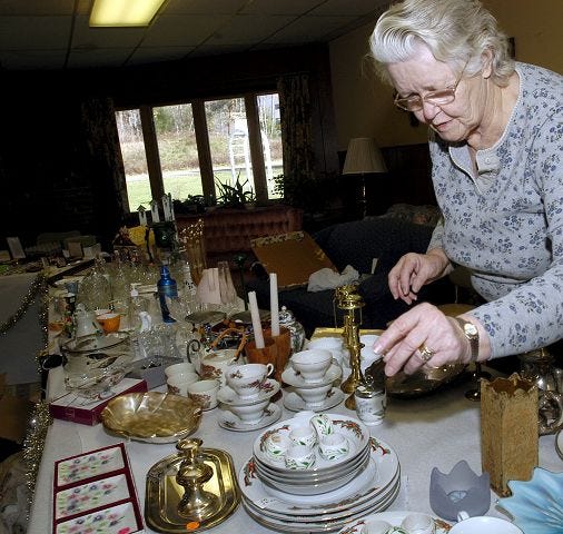 Dorothy Hetherington prepares tables with items for sale at the annual Christman Fair at the Methodist Church in Gilford which continues through today.
