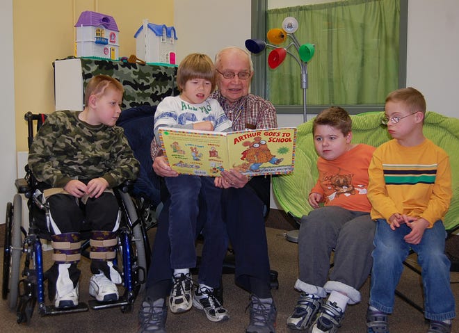 Henry Teune, who has been teaching at Zeeland Christian School since 1954, reads a book to students, from left, Logan Muiskens, Tyler VanHaitsma, Connor Hulshof and Jack Shauger in the Inclusion Program room at the school.