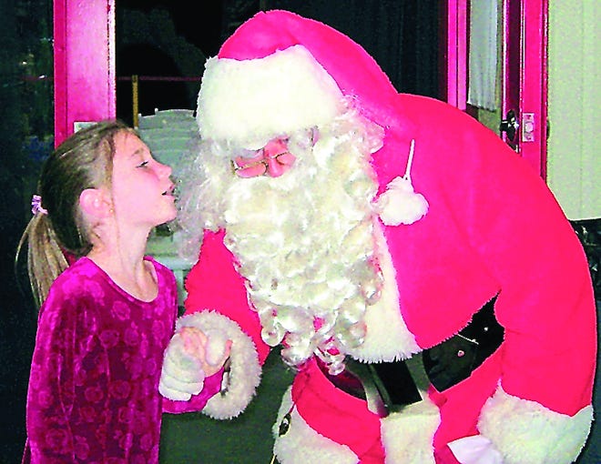 A youngster whispers in Santa's ear sharing what she wants for Christmas in this photo taken several years ago during The St. Augustine Record Holiday Short Story reception. Record file photo