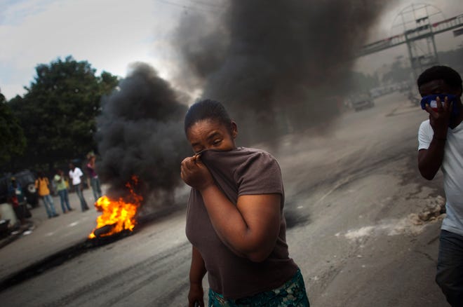 A woman covers her face to protect from the smoke of tires set on fire by demonstrators in Port-au-Prince, Haiti, on Monday. Protests began in the capital after demonstrations that began early Monday in the northern city of Cap-Haitien, where protesters threw stones at a U.N. base of Nepalese peacekeepers, whom they hold responsible for the outbreak of cholera that has killed around 1,000 people in three weeks.