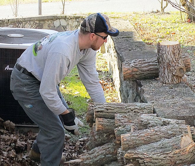 Photo by Tom Howell Jr./New Jersey Herald 
Adam Dennis stacks chopped wood Saturday from a tree that had been blown down early Wednesday on his property along Ike Williams Road in Hampton.