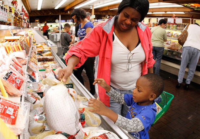 Priscilla Robinson shops for a Thanksgiving turkey with her grandson Jakarus Randolph, 4, at Ward's Supermarket in Gainesville on Saturday.