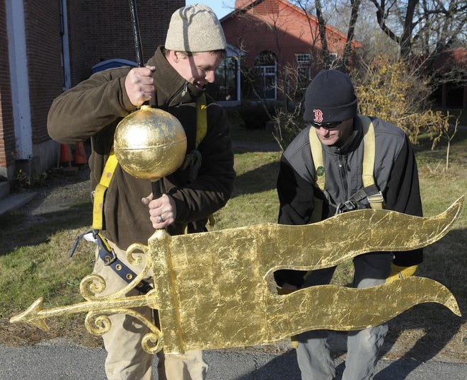 Matthew Buckley, left, and Wilson Pessoa of Murray Brothers Restorations work on the 200-year-old gold leaf weather vane that they were about to take up in a crane to put on top of the church dome.
