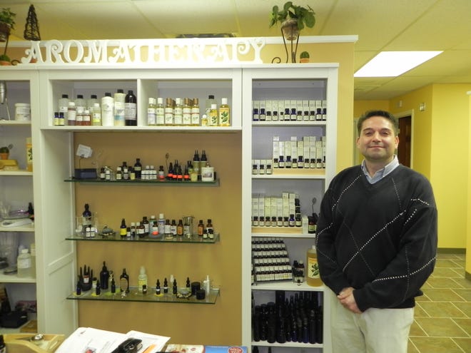Mark Carofano stands in front of the custom aromatherapy blending bar at his new shop, Earth Meets body.