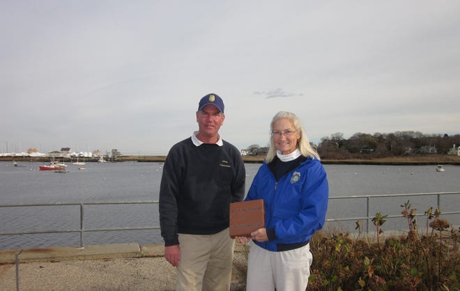 Harbormaster Mark Patterson and Assistant Harbormaster Jill West hold one of the bricks people can purchase to have their names in the expanded Harborwalk to Front Street.