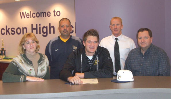 YELLOW JACKET Jackson senior Steve Cardwell signs his letter of intent with parents Ron and Debbie by his side. Behind him are Cedarville coach Mike Manes (left) and former Jackson head coach Kevin Miller.
