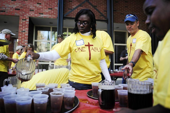 Tamara Jefferson, of Trenton, S.C., serves tea at The Alley in Aiken, where about 3,000 people gathered Thursday for a free dinner, complete with turkey, dressing and pumpkin pie. Forty-five churches support the annual One Table event.