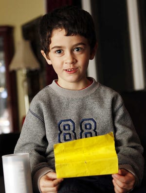 Aidan Moon, 6, reads the message he placed in a plastic tube, which he had thrown into Lake Quinsigamond.