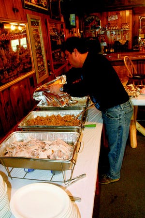 Bob Babcock, owner of Hoppie’s Tavern near Burt Lake, clears off the serving trays before the establishment’s free Thanksgiving meal Thursday. The event was open to anyone and was alcohol free.