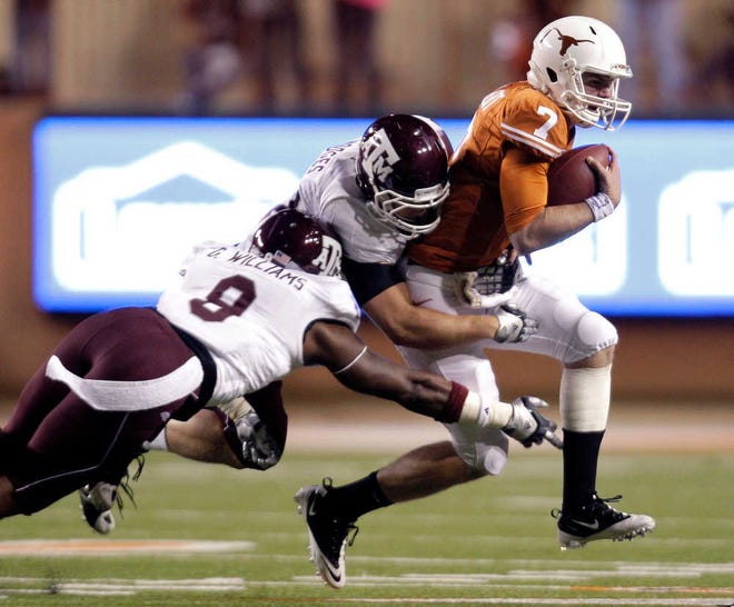 Texas’ Garrett Gilbert (7) is stopped by Texas A&M’s Charlie Thomas (9) and Michael Hodges, center, during their game Thursday in Austin. The No. 17 Aggies won, 24-17.
