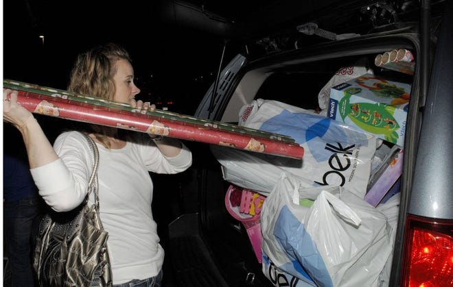 TERRY DICKSON/The Times-UnionTanya Causey of Brantley County looks for a place to jam Christmas wrap into Christi Stewart's already-loaded SUV in Brunswick. Causey said some items had fallen out at some of their stops.