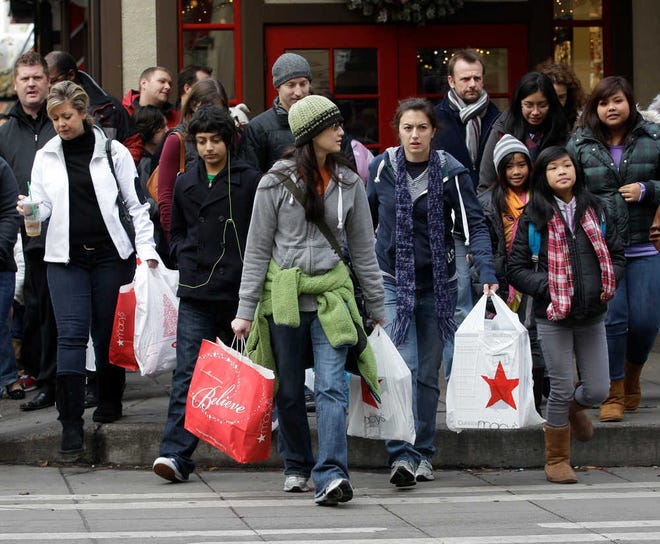 Shoppers carry their bags as they walk in downtown Seattle on Friday, Nov. 26, 2010. (AP Photo/Ted S. Warren)