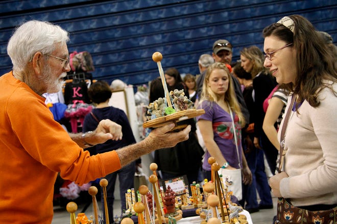 Emmett Sweeny, left, of Inverness, shows UF graduate student Kristina Socarras a musical carousel made by Sweeny and his wife, Sue, for the annual Craft Festival at the O'Connell Center in Gainesville on Saturday.