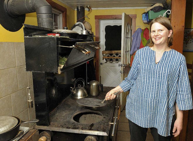 Melanie Cruz stands at the family's wood cook stove in their home in Barre. The Cruzes cook all of their meals and heat water for washing clothes and dishes and “bucket” bathing.