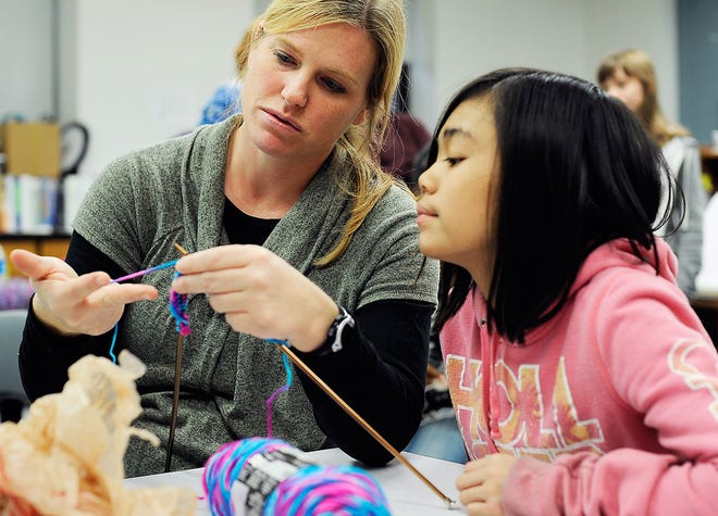 Smithton Middle School teacher Ashley Malorin, left, checks out a knitting project of sixth-grader Cindy Stoll during the first meeting of the school’s knitting club.