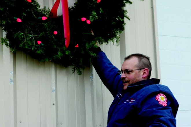 Firefighter Dan Chard hands the wreath for the Keep the Wreath Red campaign at the new fire station Thursday morning.