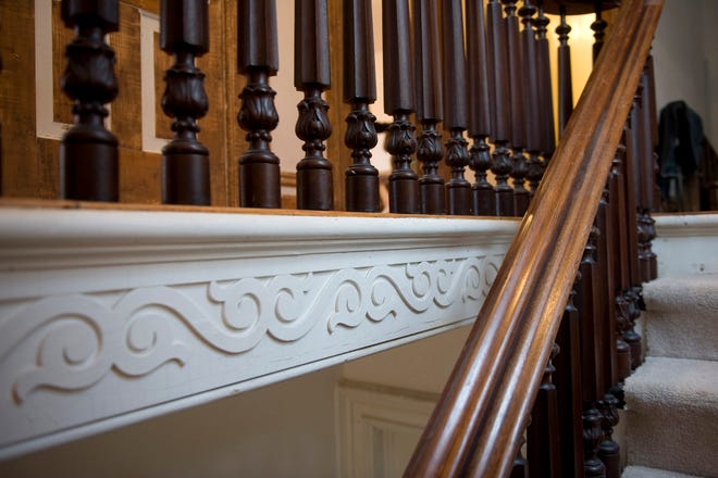 A walnut railing leads to the second floor in the Monmouth home of Tim and Elke Narkiewicz where decorative wooden scrollwork, original to the house, remains.