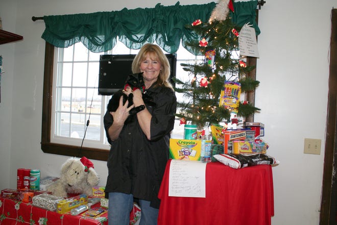 Particular Pets owner Linda McPherson holds kitten Willow in front of the assortment of items ready to be donated to Boyce Elementary.