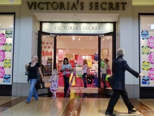 SHOPPERS WALK past a Victoria's Secret store, in Des Peres, Mo. Several companies that peddle affordable luxury goods are reporting stronger-than-expected earnings, suggesting shoppers are making modest splurges.
