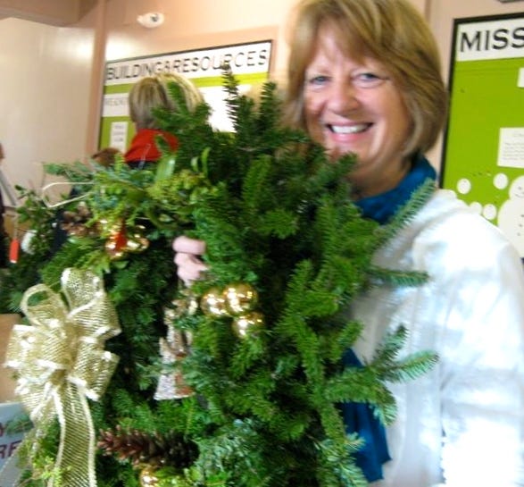 The Wollaston Garden Club held its annual holiday greens sale Saturday. Club member Karen Lundsgaard holds one of the many wreaths that were sold. 
Sue Scheible/The Patriot Ledger