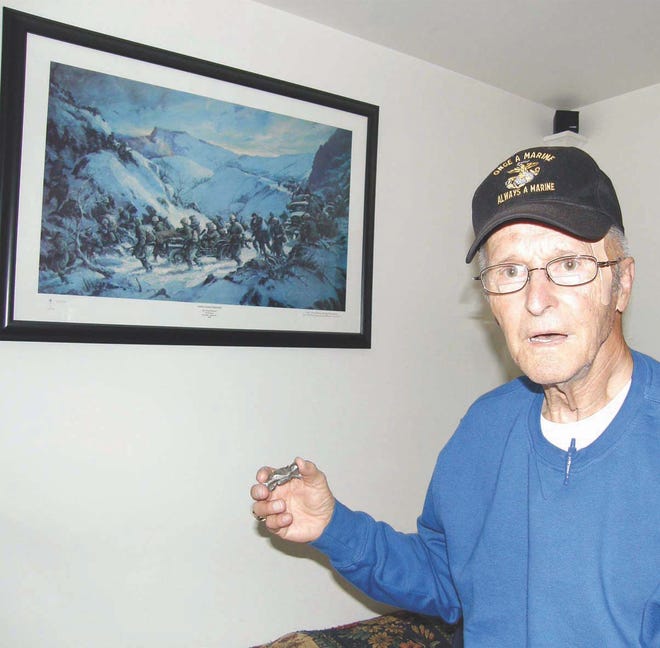 Korean War veteran Paul Summers holds a piece of shrapnel that nearly hit his knee during the Battle of Chosin Reservoir in the winter of 1950. A depiction of the battle hangs on the wall behind him. Summers shared his experiences at Chosin with the West Point Center for Oral History in November.