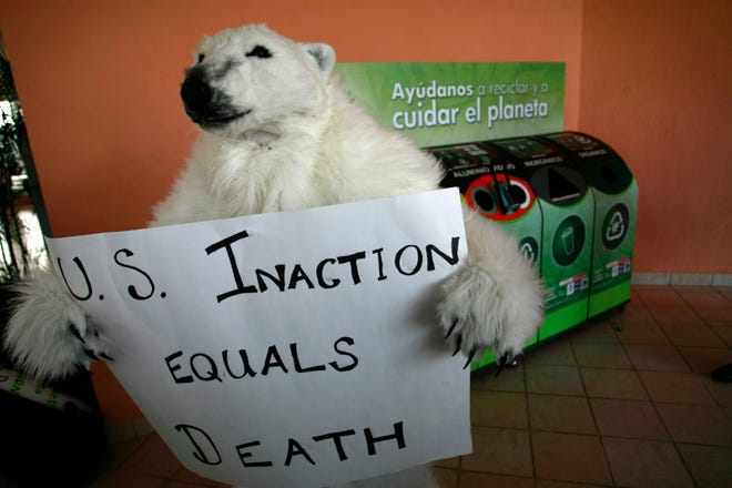 An activist disguised as a polar bear holds up a sign at the Moon Palace Hotel during the United Nations Climate Change Conference in Cancun, Mexico,Thursday, Dec. 9. With just two days left, delegates to the annual U.N. climate conference haggled and cajoled into the night in search of compromise on a raft of issues, including whether industrial nations should generate $100 billion a year, or up to $600 billion, to help poorer countries cope with global warming.