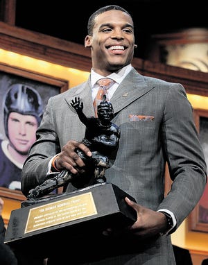 In this photo provided by the Heisman Trophy Trust, Auburn quarterback Cam Newton picks up the Heisman Trophy after his acceptance speech following being named the Heisman Trophy winner, Saturday, Dec. 11, 2010, in New York.