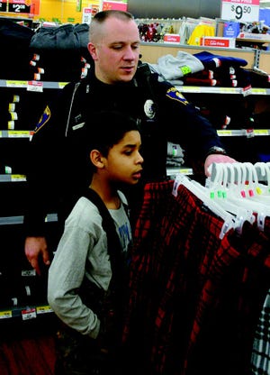 Drew DeCambre of Mackinaw City looks at pajama pants with a little help from patrolman John R. House of the Mackinaw City Police Department during the annual “Shop With a Hero” event at the Cheboygan WalMart Monday. Just over $6,500 was raised to benefit 45 kids in attendance, getting assistance from representatives of nine area law enforcement and fire department agencies.