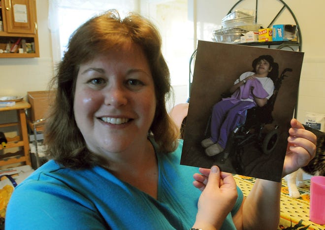 Jennifer Sharpe holds a picture of her daughter, Rachael, 11, at their home in Mendon, Thursday.